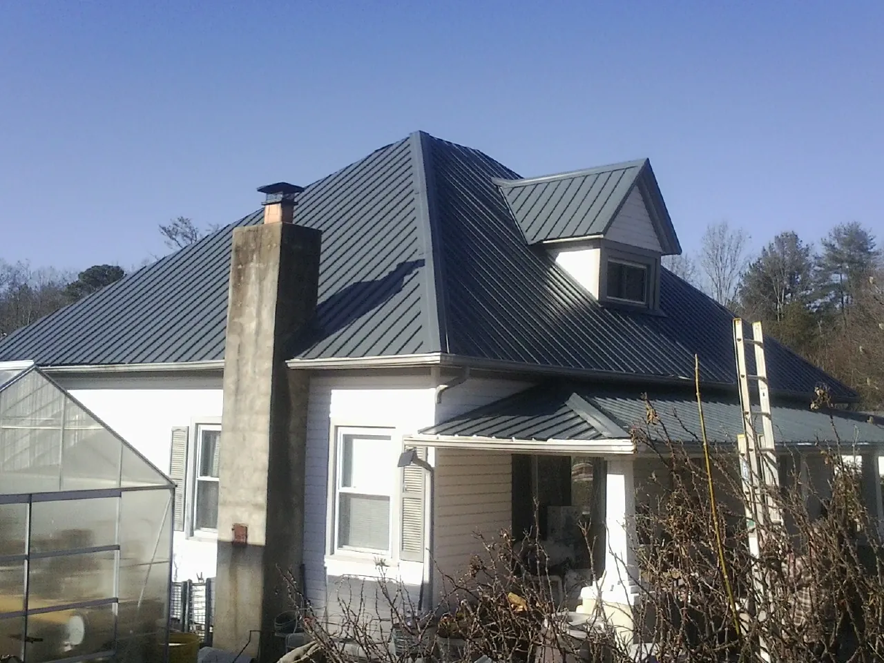 Dark blue standing seam metal roof on a white farmhouse with dormer — Slate & Tile Roof Repair by Roofing Brothers in Queen Creek