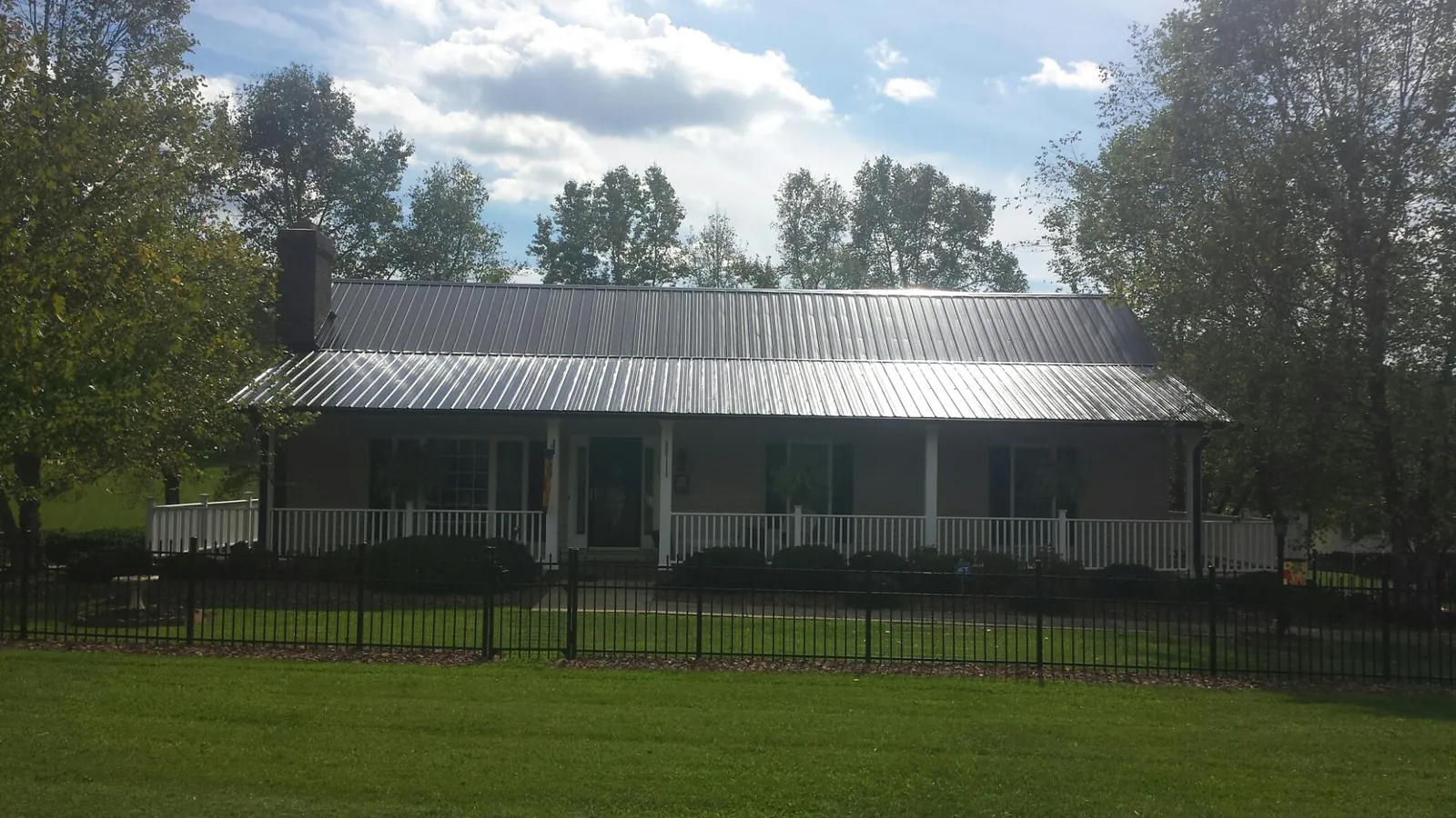Gray metal roof on a brick ranch with a full width front porch — Gutter Guard Installation work by our crew in Queen Creek