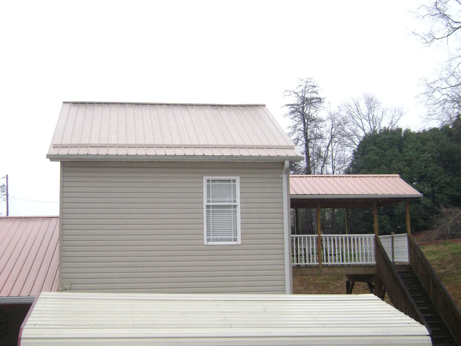Tan metal roofs on a two story addition and attached porch, from a Roof Replacement job in Queen Creek
