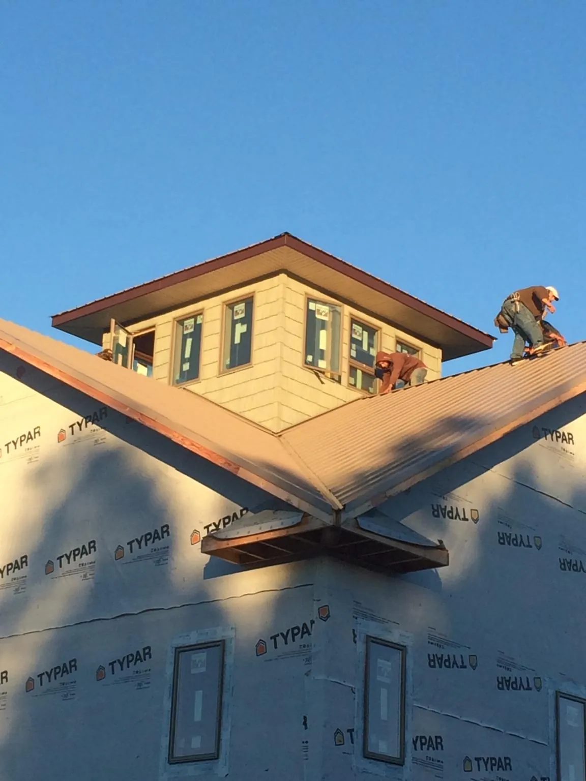 Roofers working around a rooftop cupola on a new metal roof at sunset — Roof Waterproofing in Queen Creek by Roofing Brothers